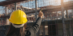 Lady with a safety helmet on pointing at a construction site.